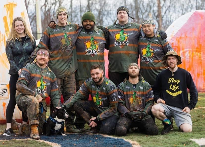 Team Slugs posing on the field at Matts Outback Paintball with their mascot dog